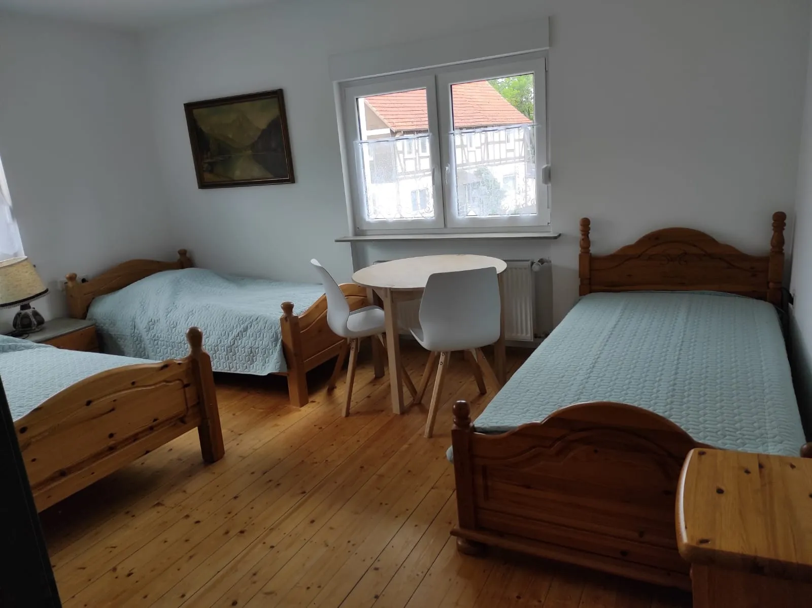 Helles Schlafzimmer mit drei Einzelbetten und Sitzecke am Fenster
