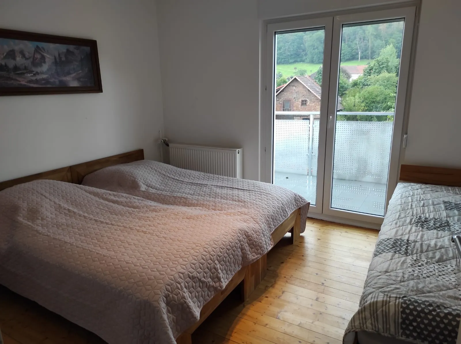 Schlafzimmer mit Doppelbett und Einzelbett sowie Zugang zum Balkon
