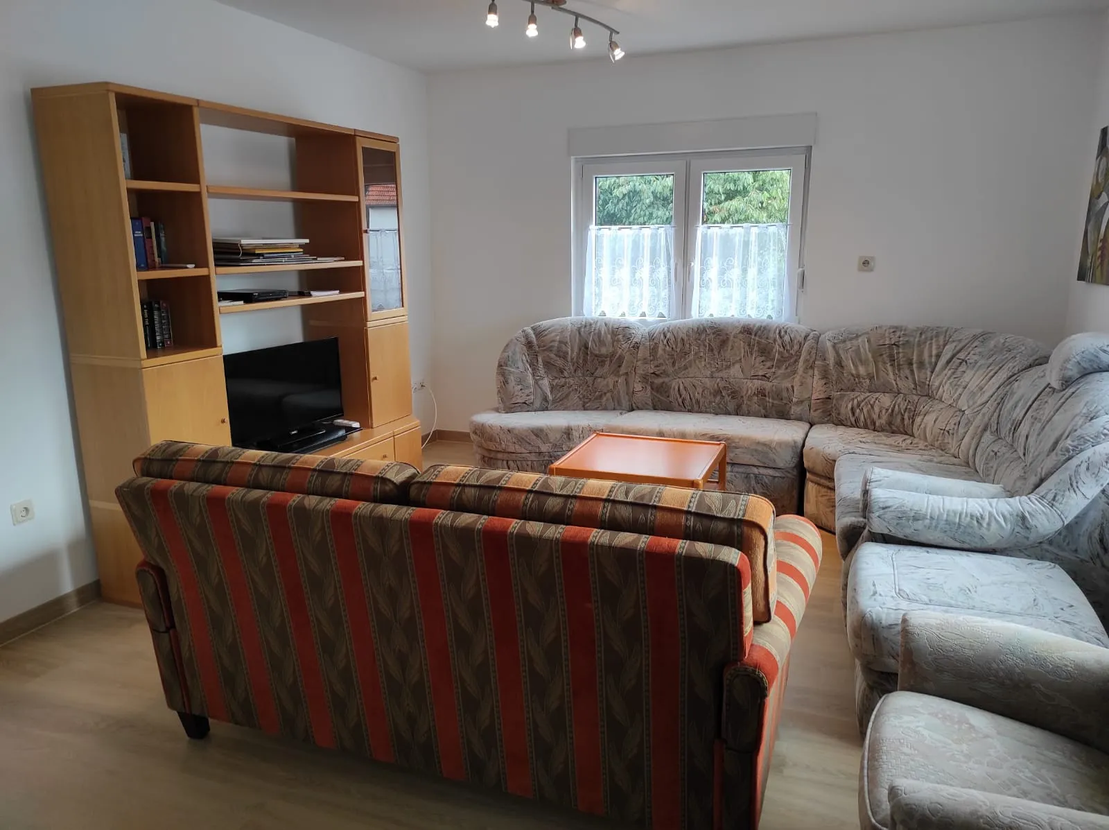 Wohnzimmer mit Sitzgruppe, Schrankwand und Flachbildfernseher